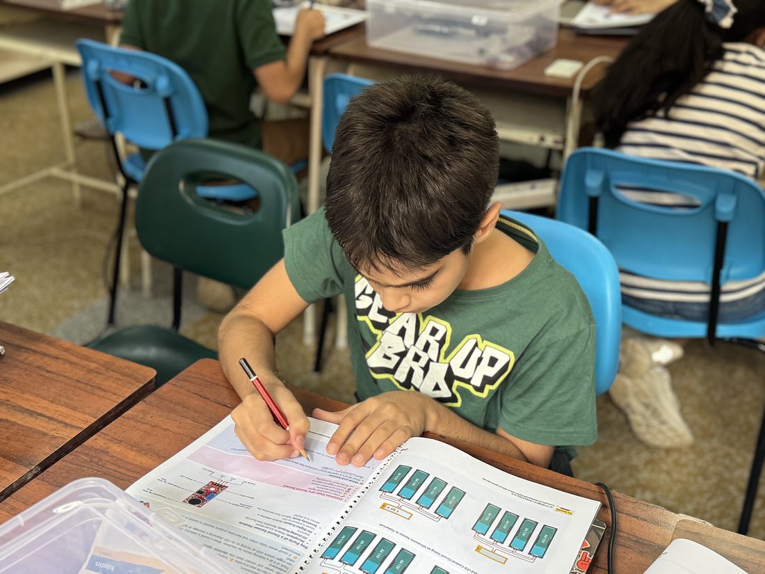 A student writing answers in a workbook during a classroom session.