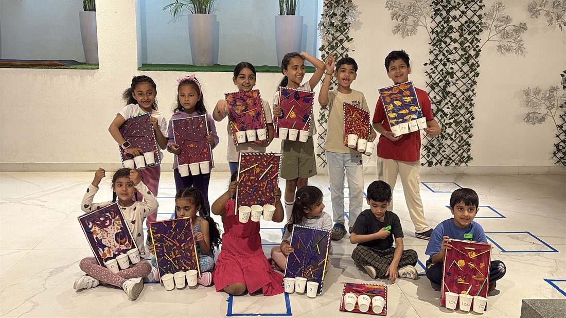 A large group of children posing together, each holding a craft board they built.
