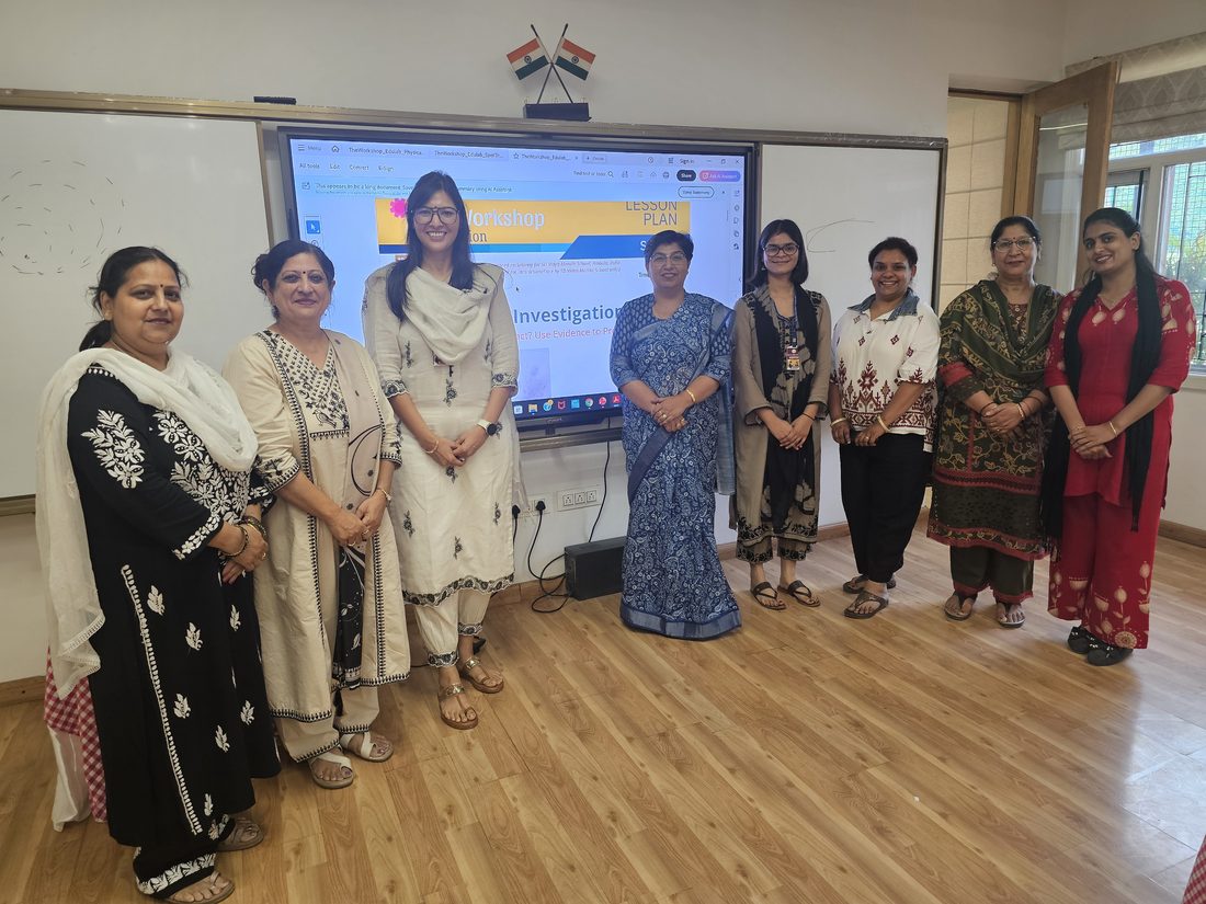 A group of teachers standing together in front of a presentation screen mid-session.