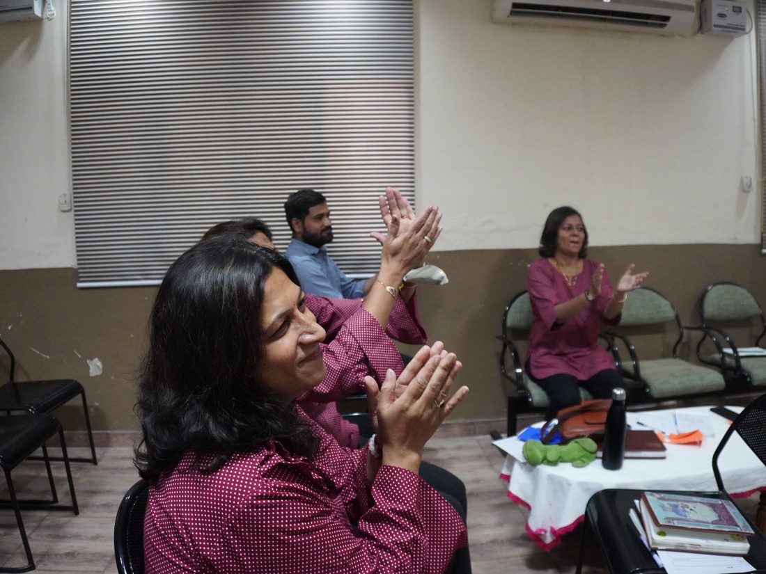 Teachers applauding during a training session in a classroom.