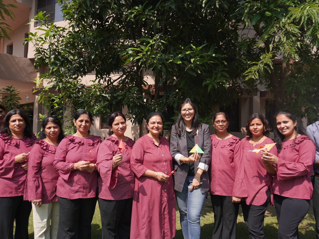 A large group of teachers posing together outdoors under a tree after a training session.