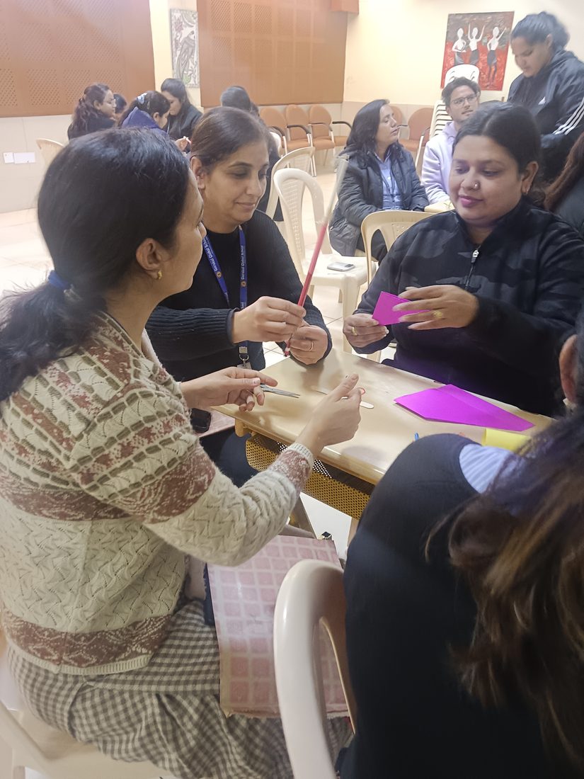 Teachers gathered closely around a table working through a hands-on exercise.
