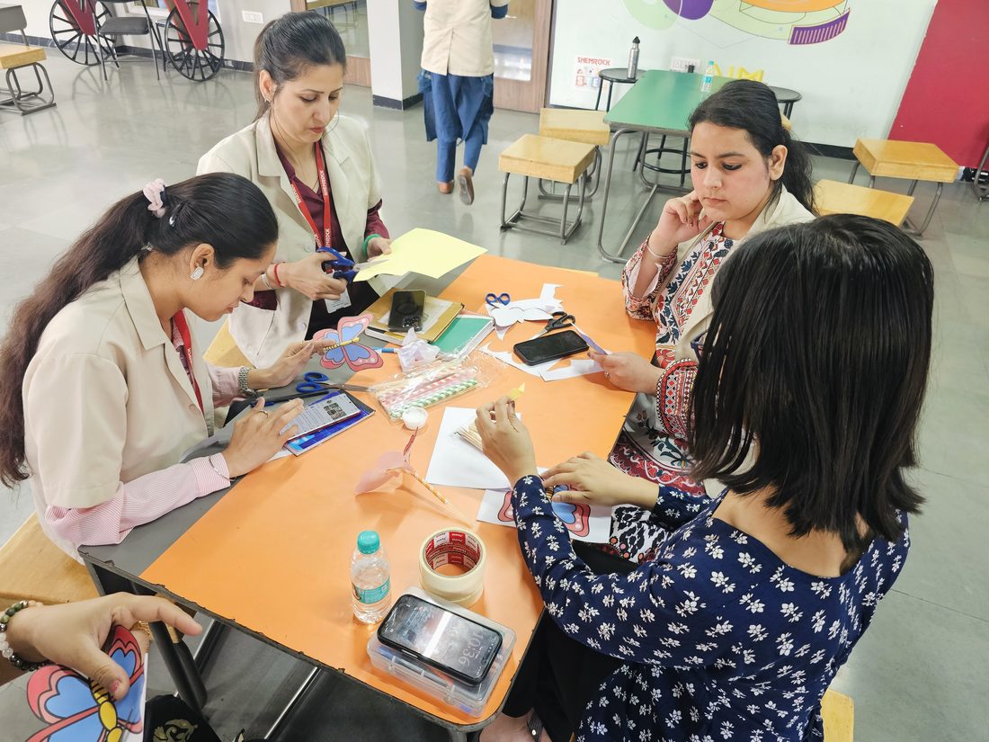 An overhead view of teachers collaborating on a craft activity at a table.